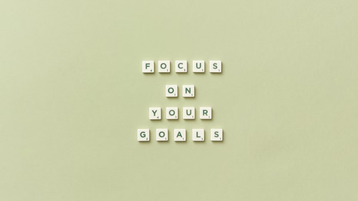 Scrabble letters forming a motivational phrase 'Focus on Your Goals' on a light green background.